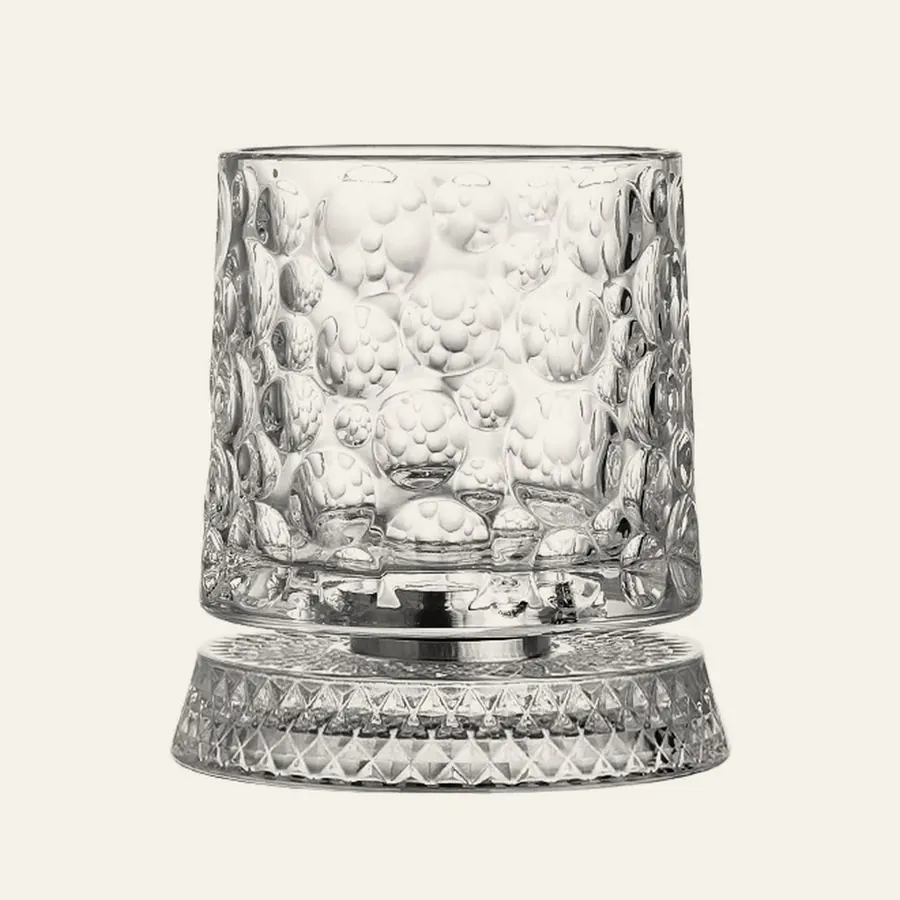 Spinning whiskey glass with a bubble texture on its clear spinning base